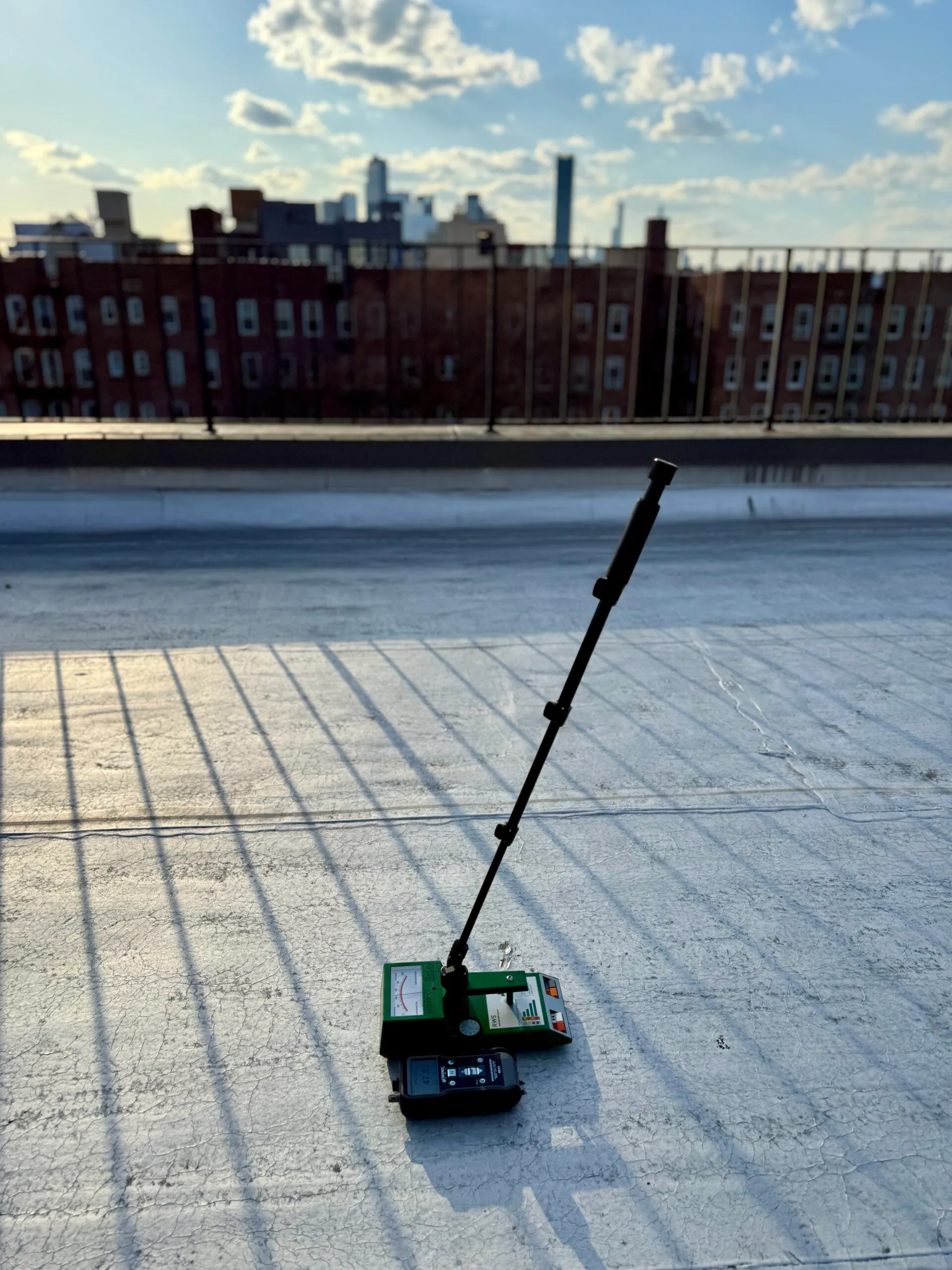 Moisture detection equipment on a flat roof with city skyline in background.